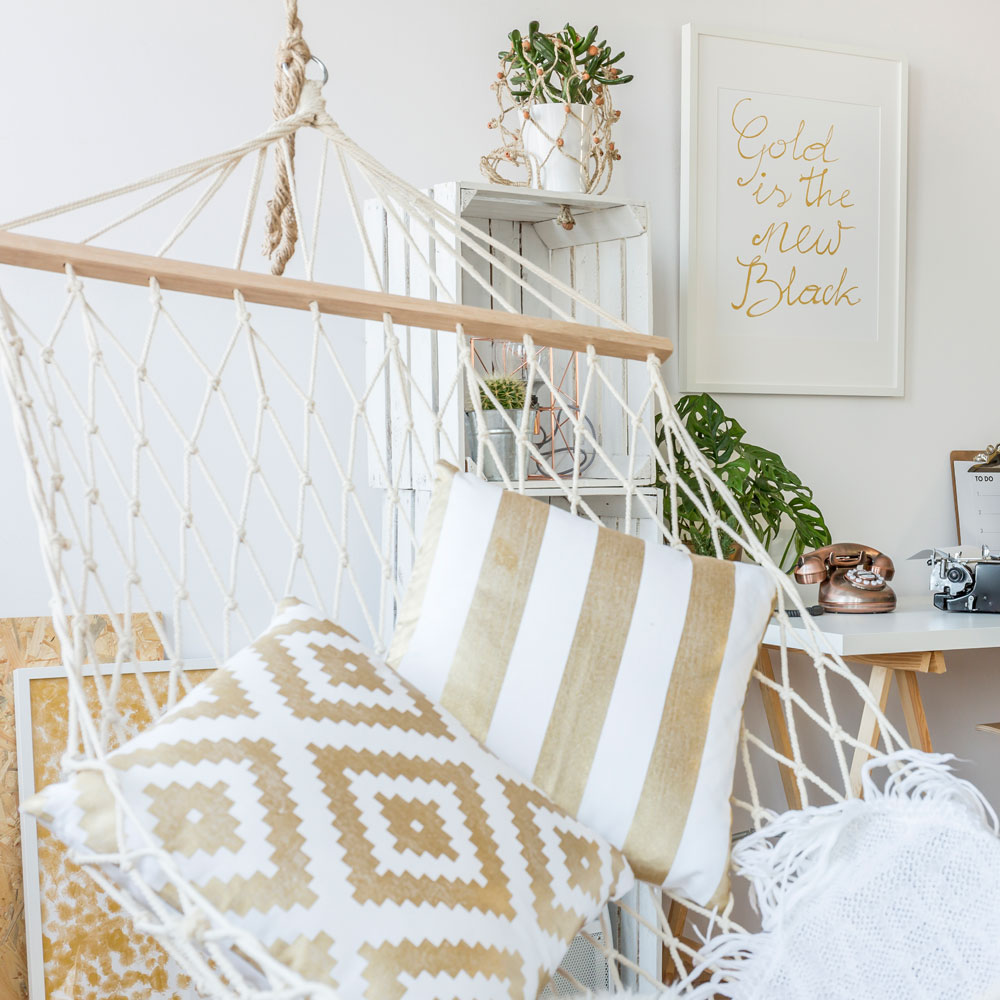 Hängesessel aus Makramee mit Kissen und Pflanzen im gemütlichen Boho Wohnstil